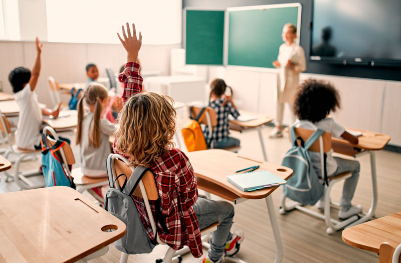 students in classroom raising their hands
