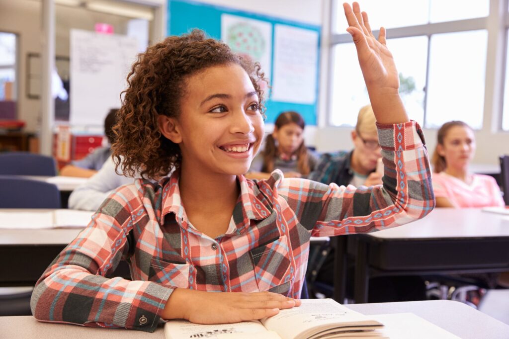 young girl raising her hand in class